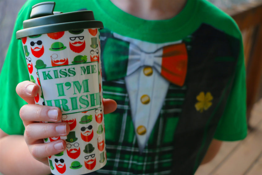 Person holding St. Patrick’s Day themed mug.