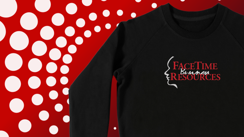 A black sweatshirt branded with the Facetime Business Resources logo sits on a field of red with white spheres forming concentric circles outward.